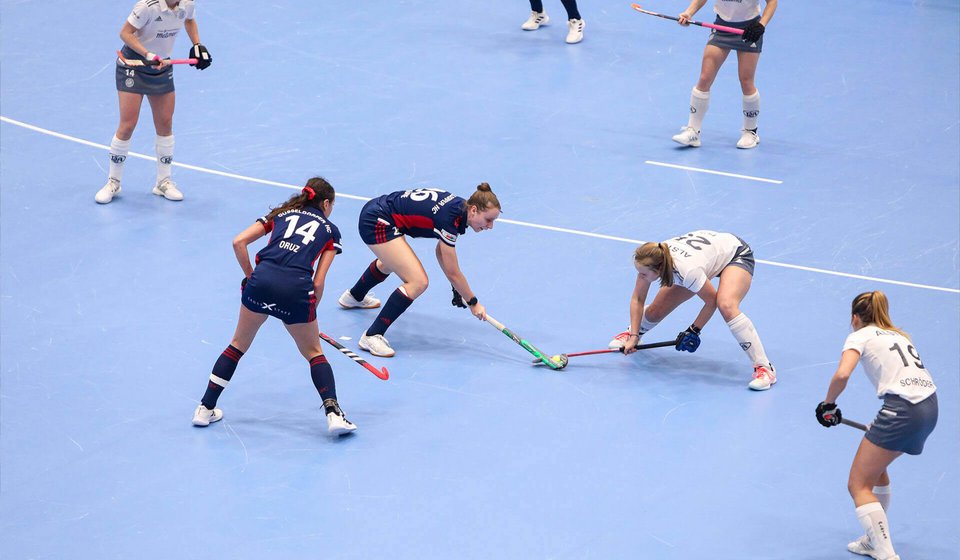 Zwei Hockey-Spielerinnen aus verschiedenen Mannschaften ringen um den Ball. 