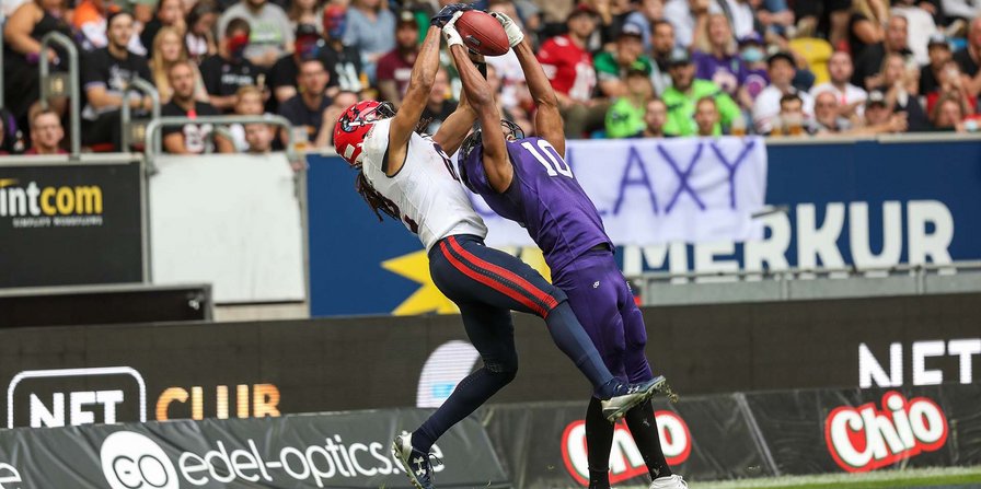 Zwei American-Football-Spieler aus verschiedenen Mannschaften kämpfen um den Ball. 