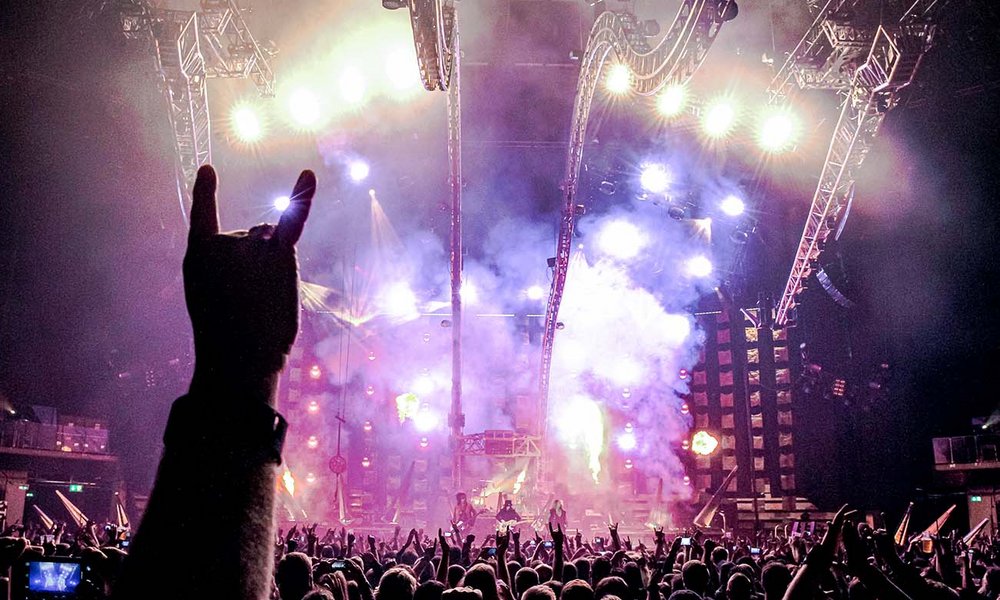 Bild aus der Menge mit Blick auf die Bühne beim Konzert von Alice Cooper & Moetley Crue. Im Vordergrund wird eine Hand in die Luft gehalten, die den kleinen Finger und den Zeigefinger nach oben streckt.